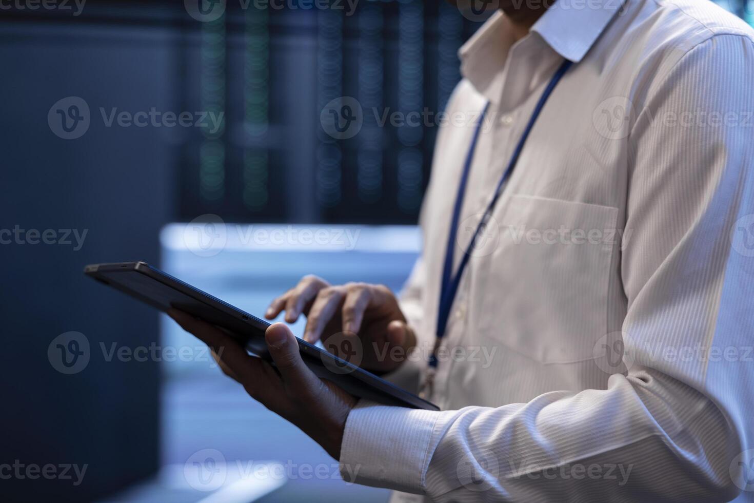 Engineer working in high tech server farm, using laptop and tablet to analyze data, ensuring seamless data flow. Man examining hardware in data center, ensuring system integrity and security, close up photo