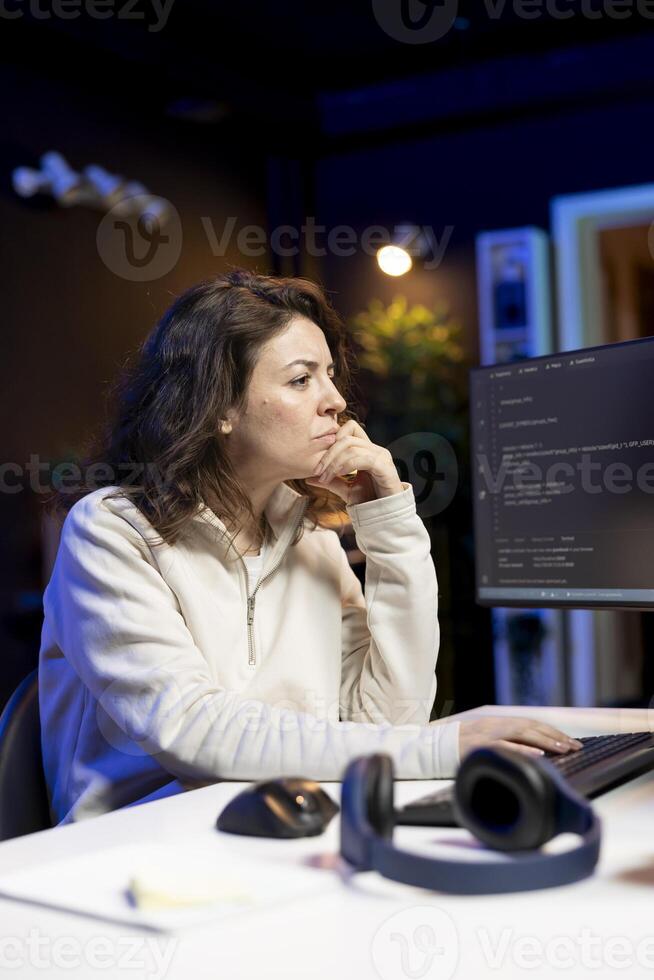 Freelancer doing software debugging using computer, checking errors in lines of code displayed on PC monitors. IT professional in apartment fixing coding issues using desktop PC photo
