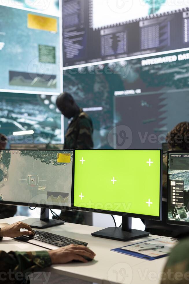 Trooper following CCTV satellite surveillance on pc next to isolated mockup screen, tracking deployed units with GPS location. Army conscript operating in command post headquarters. photo