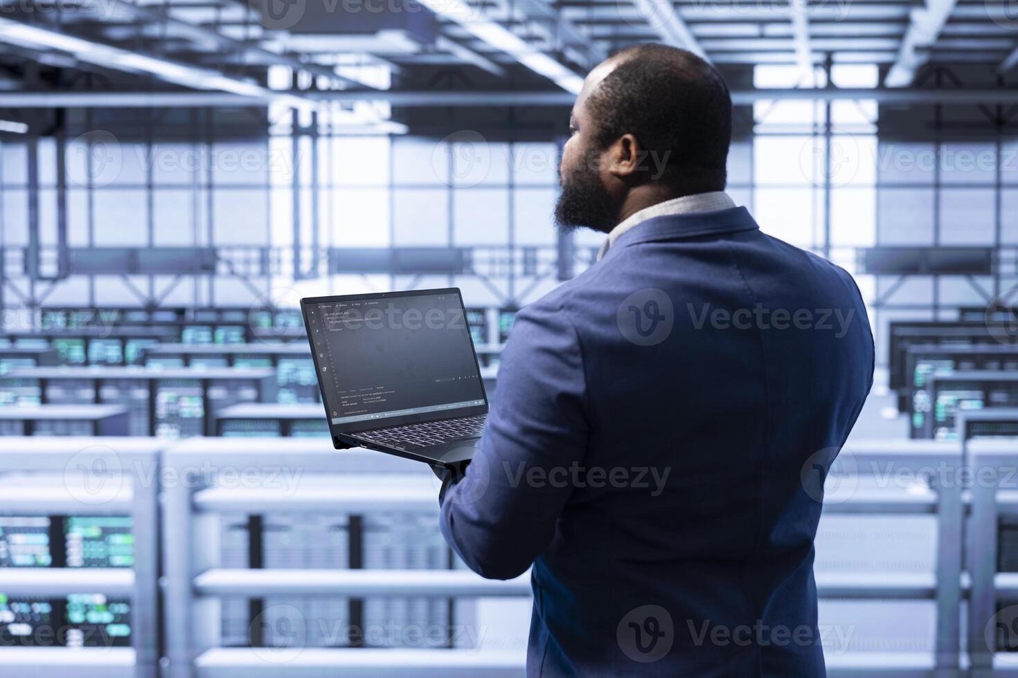 IT staff member in data center implementing backup solutions to protect against infrastructure data loss using laptop. IT professional resolving technical difficulties affecting rigs using notebook photo