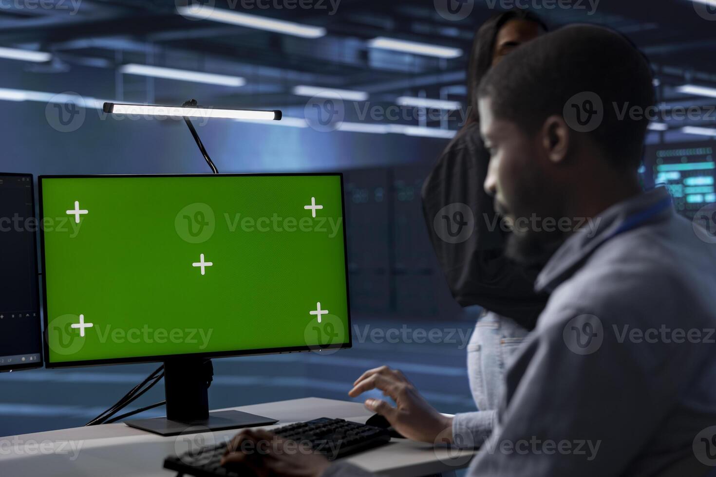 Admin in data center running system diagnostic tests using green screen computer display. Worker in server room deploying error checking utilities on chroma key desktop PC to repair network issues photo