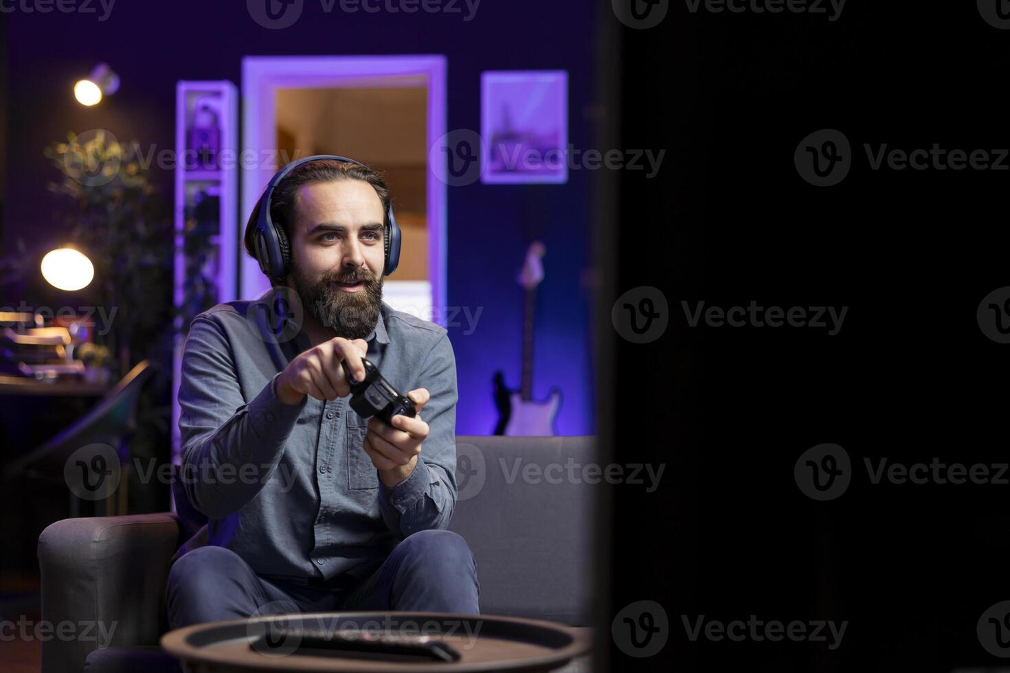 Joyous man having fun while playing videogames on gaming console with teammates, talking through headphones. Lively gamer chatting with friends through headset while defeating players online photo