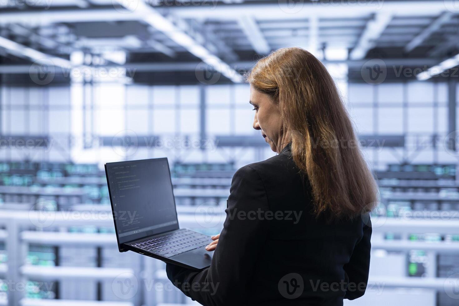Technician in data center checking rigs and hardware, doing maintenance. IT specialist planning and executing high tech server hub facility migrations and upgrades using notebook photo