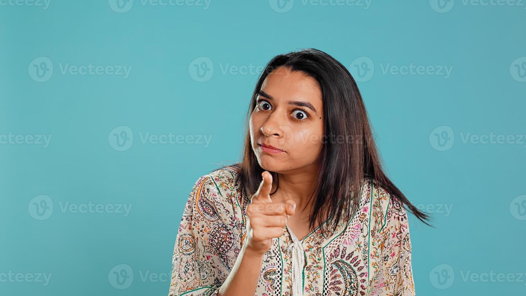 Irked indian woman fighting with boyfriend, doing scolding gesturing, isolated over studio background. Outraged wife arguing with husband during conversation, doing angry hand gestures, camera B photo