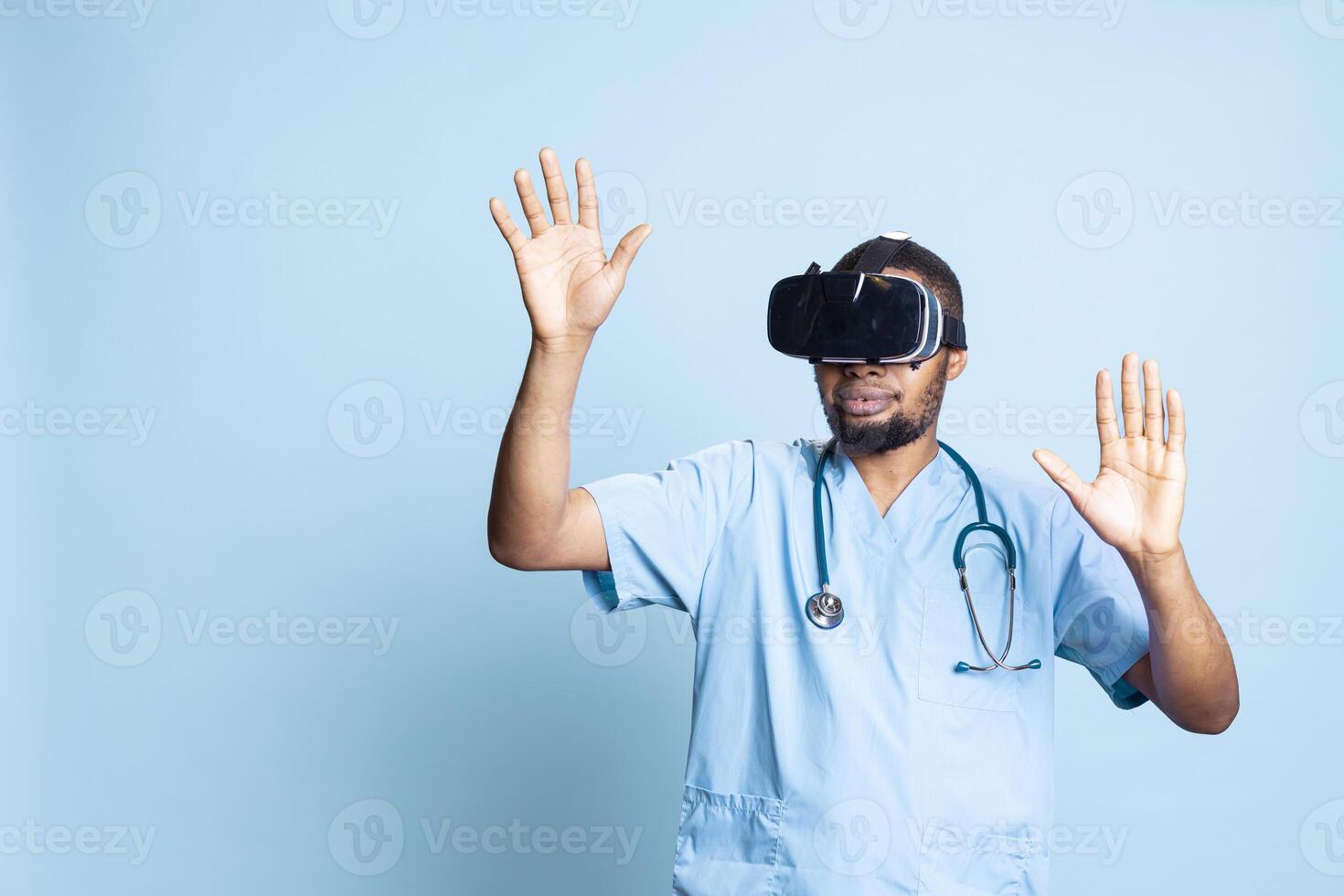 Nurse wearing virtual reality headset remotely operating patient. Healthcare specialist using high tech futuristic modern medical vr gadget, standing against blue background in studio. photo