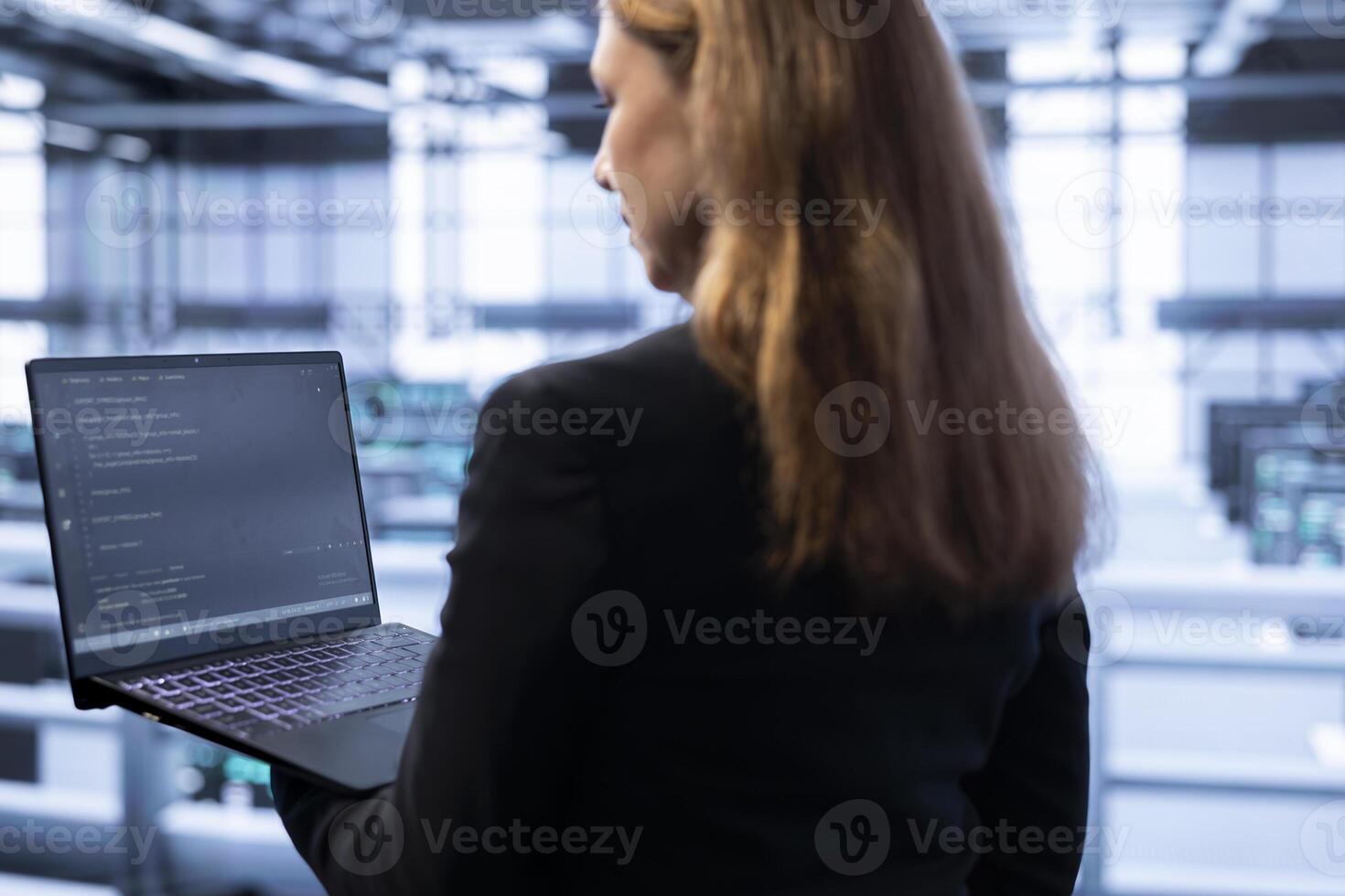 Engineer in data center tracking network traffic and activity, installing and configuring software updates using laptop. IT employee performing database backups to protect user information photo