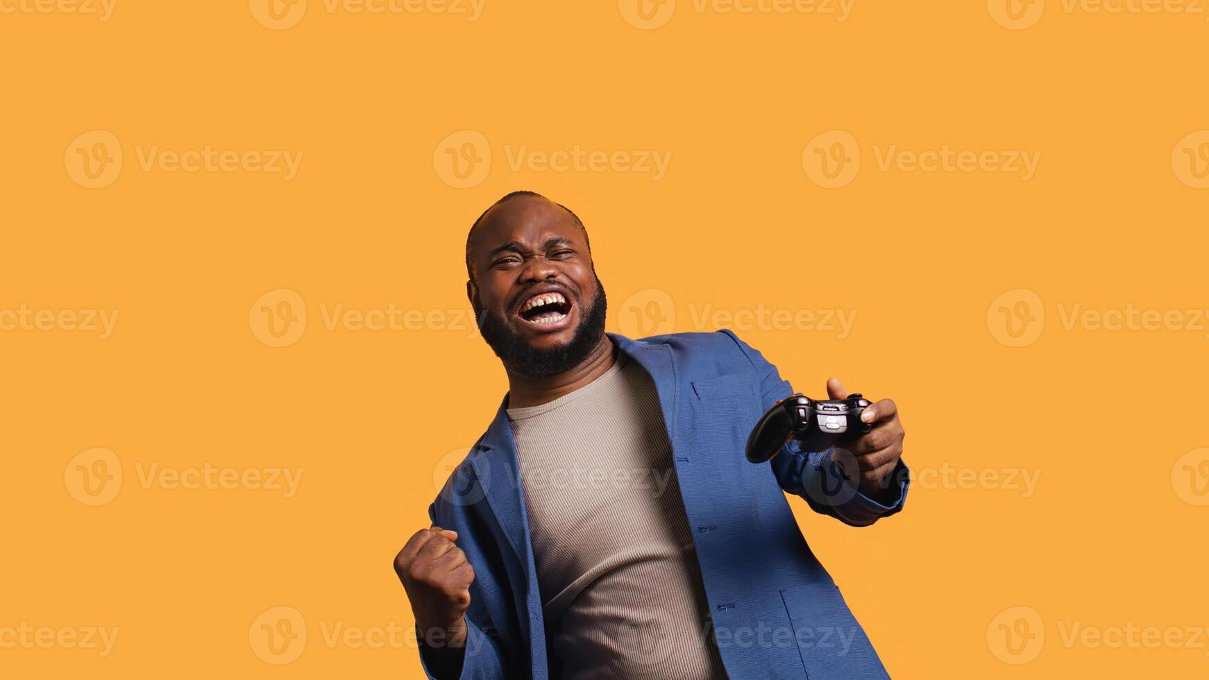 Joyous BIPOC gamer celebrating after winning gaming console game, studio background. Delighted man bragging after being victorious in videogame, defeating all enemies using gamepad, camera B photo