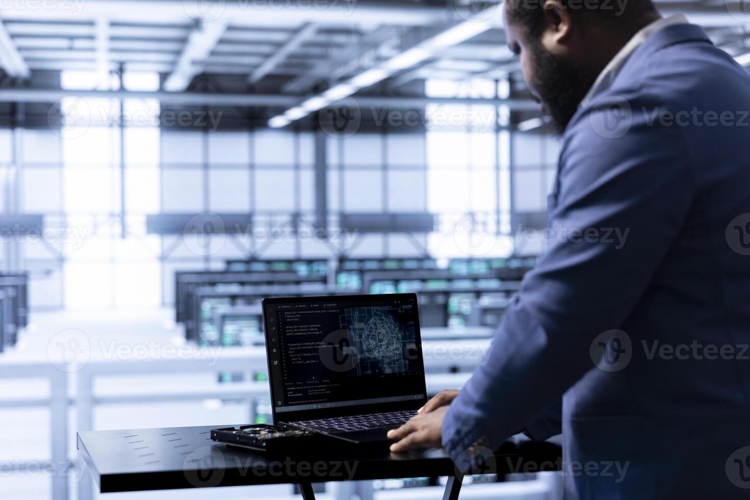 Computer scientist in data center using laptop to visualize artificial intelligence neural networks made up of interconnected nodes. African american man oversees AI systems processing information photo