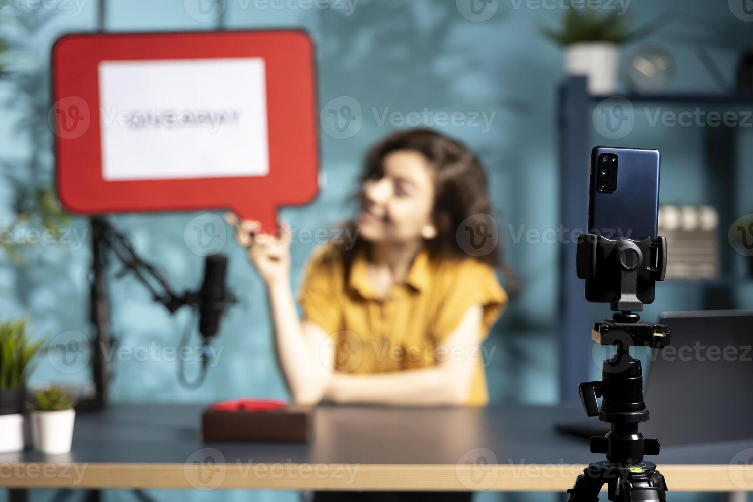 Focus on smartphone used by content creator holding empty copy space sign to record giveaway for fans. Close up of phone used by internet star to film in studio, offering gift, holding cutout photo