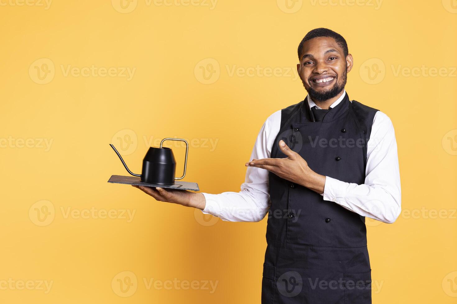 Restaurant butler serving people with tea before their dinner order, bringing the teapot at the table for professionalism. Waiter serves clients for satisfaction, service oriented industry. photo