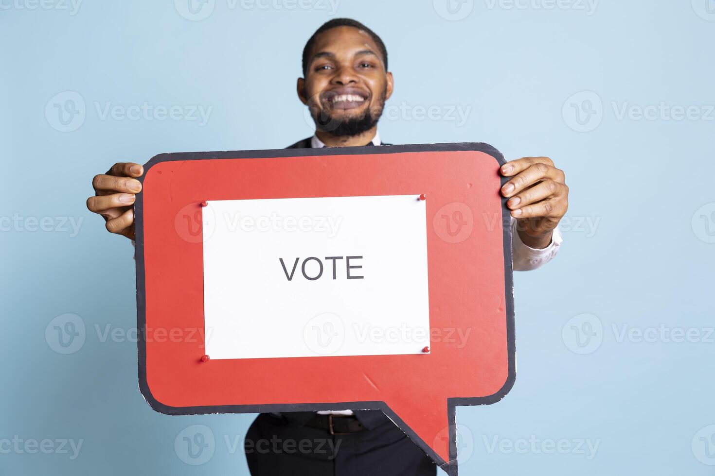 Hotel concierge holding a speech bubble with the message to vote, urging people to get interested in politics on camera. Skilled bellhop with suit and tie showing a marketing ad icon. photo