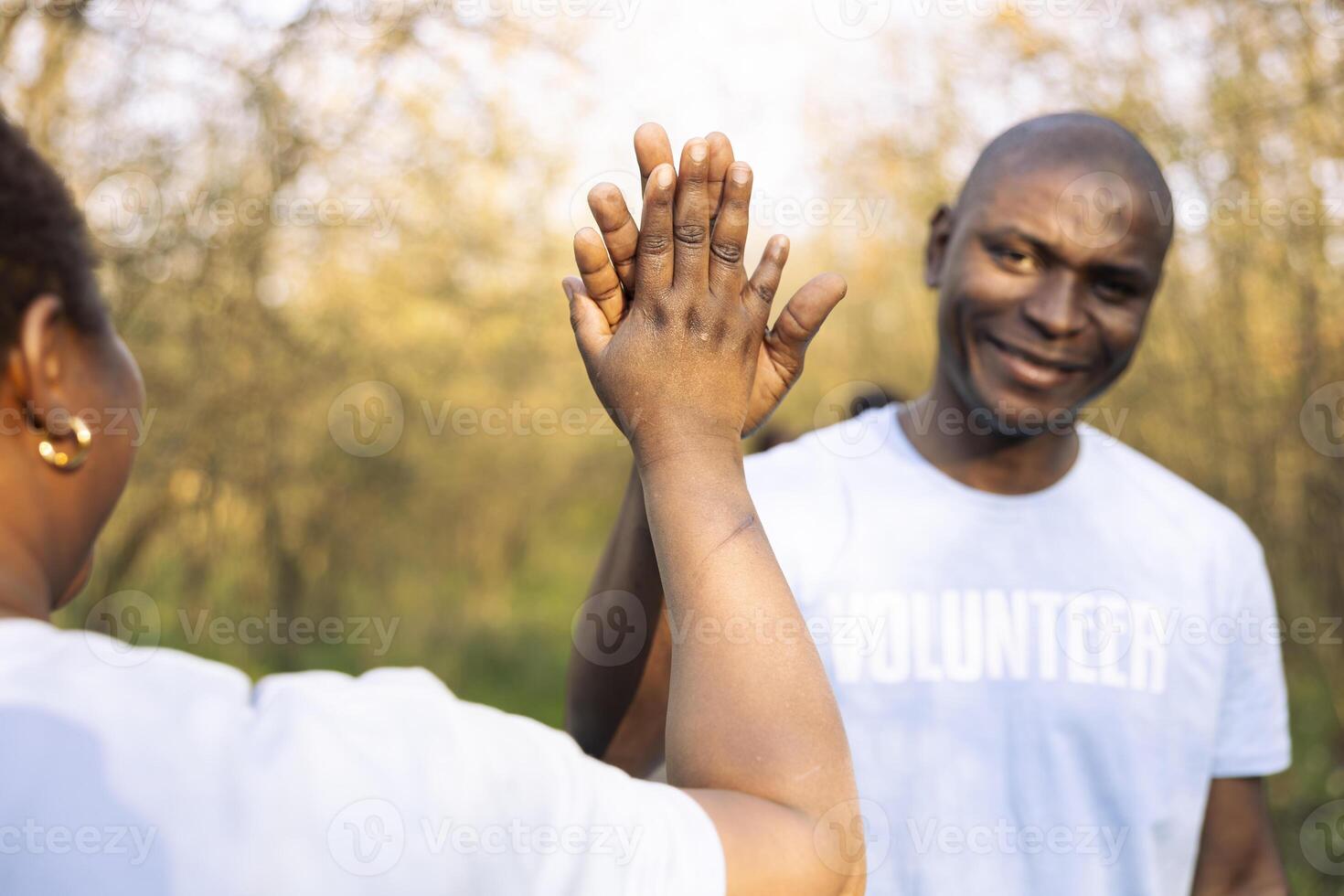 African american volunteers doing high five praising each other after a successful environmental mission, finishing junk and plastic cleanup. Joyful activists enjoying their job well done. photo