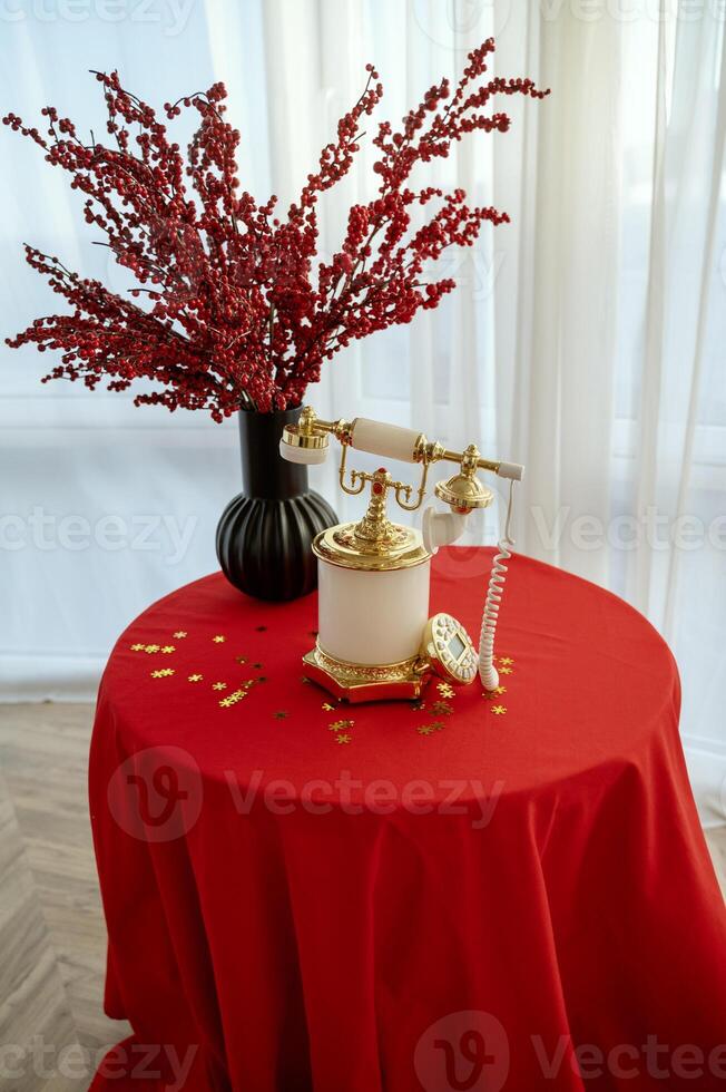 There is a vintage white telephone on the table. The table is covered with a white tablecloth. photo