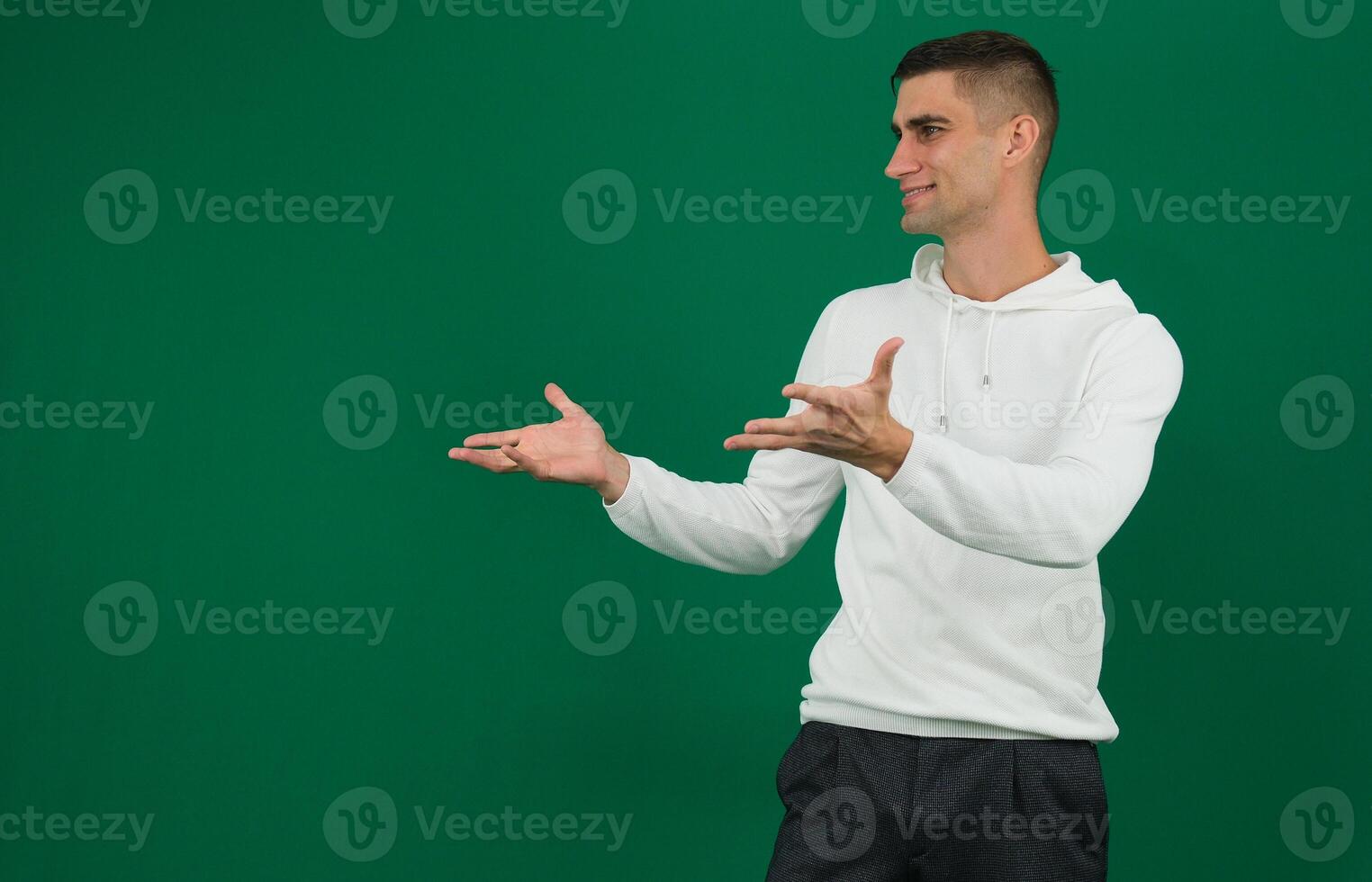 Photo of amazing salesman guy in excited mood indicating finger to empty space advising cool shopping prices wear casual denim shirt isolated green color background