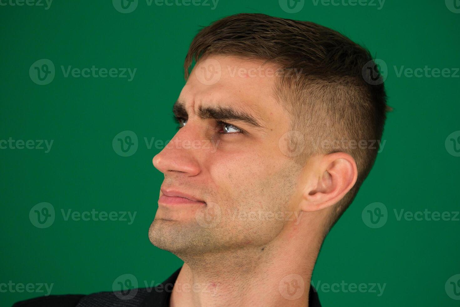 young handsome man feeling happy, proud and hopeful, wondering or thinking, looking up to copy space with crossed arms photo