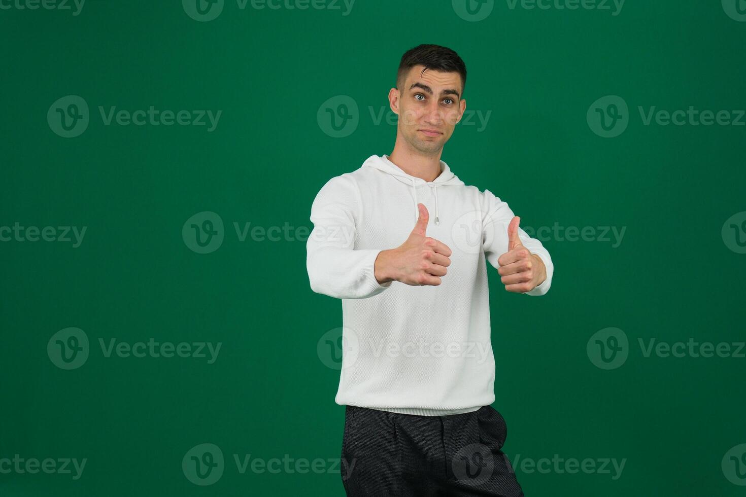 Young indian man wearing purple sweatshirt standing over isolated pink background success sign doing positive gesture with hand, thumbs up smiling and happy. Cheerful expression and winner gesture. photo