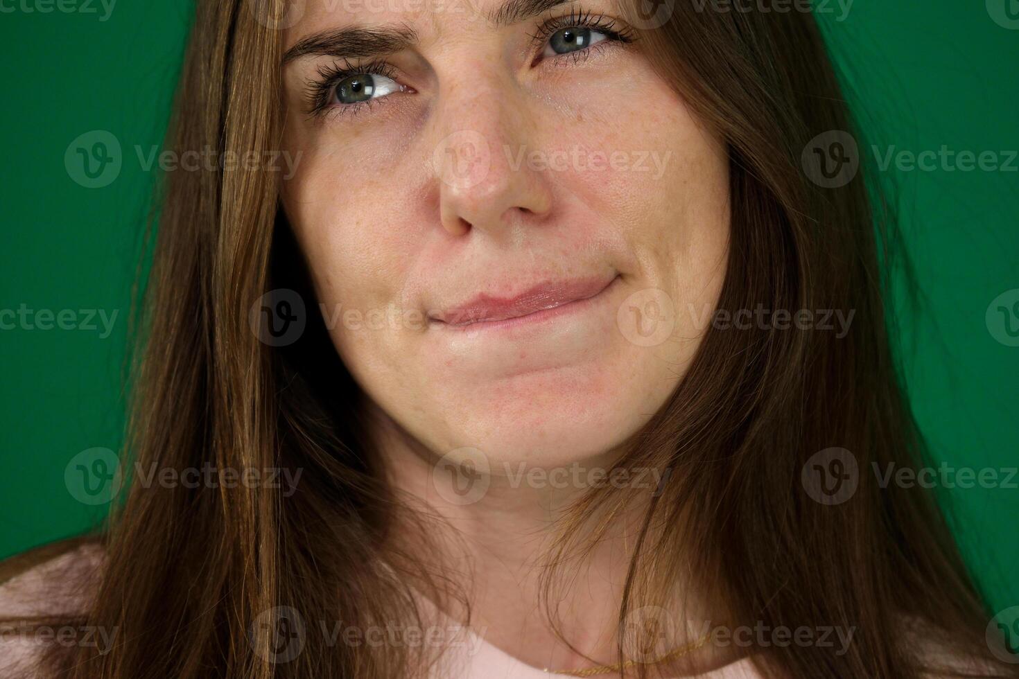 Thoughtful Asian woman keeps hand on chin looks pensively above dressed in casual blue jumper poses against brown background blank copy space for your advertising content thinks about future photo