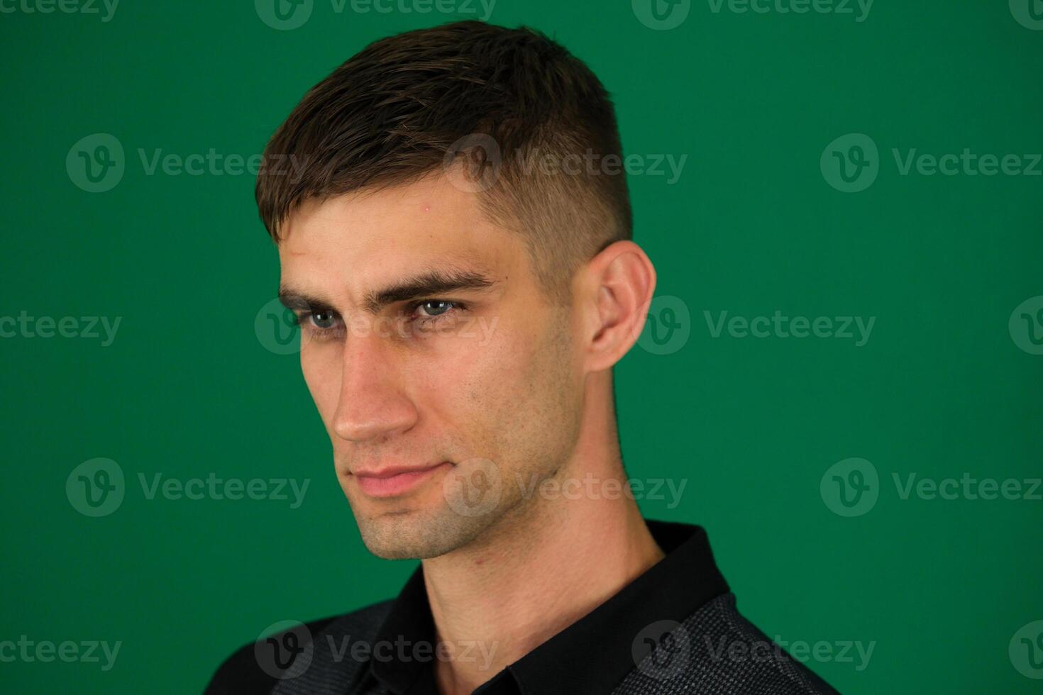 emotions of a handsome man guy on a green background chromakey close-up dark hair young man photo