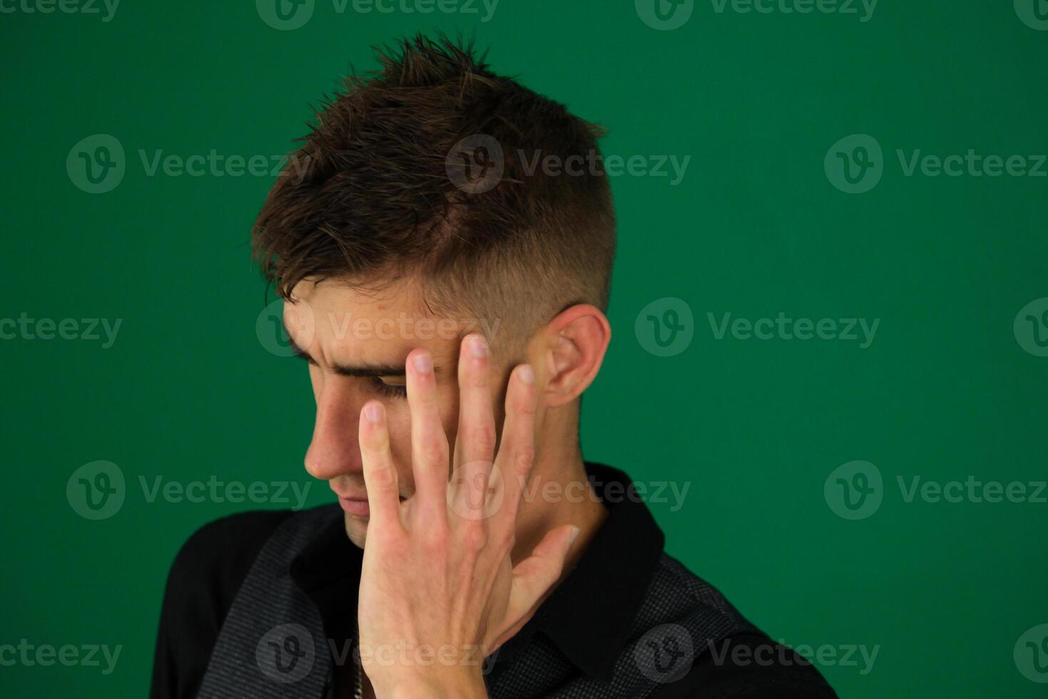 Handsome man with blue eyes and beard wearing denim jacket peeking in shock covering face and eyes with hand, looking through fingers with embarrassed expression. photo