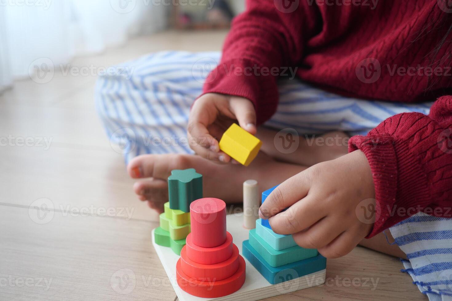 A Child Enjoys Playing with Vibrant and Colorful Stacking Toys on a Wooden Floor photo
