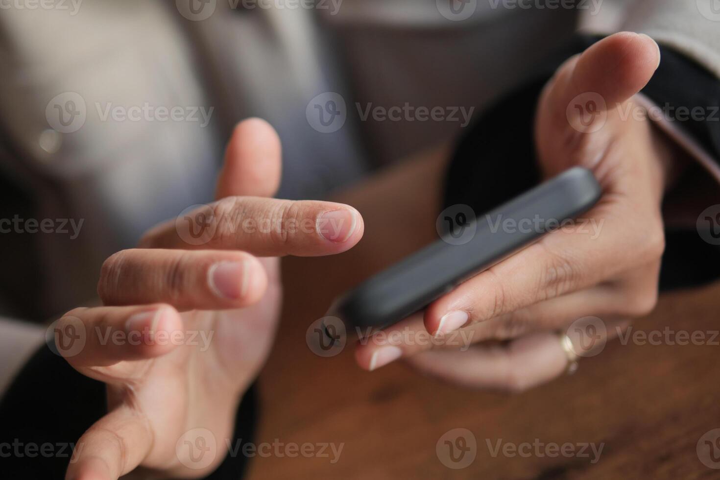 A detailed closeup view of hands utilizing a smartphone on a wooden table photo