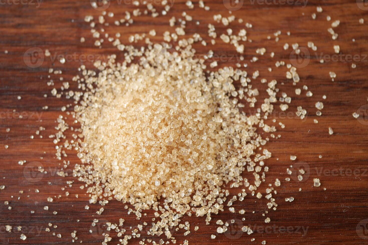This image features a closeup view of a pile of brown sugar resting on a wooden surface photo