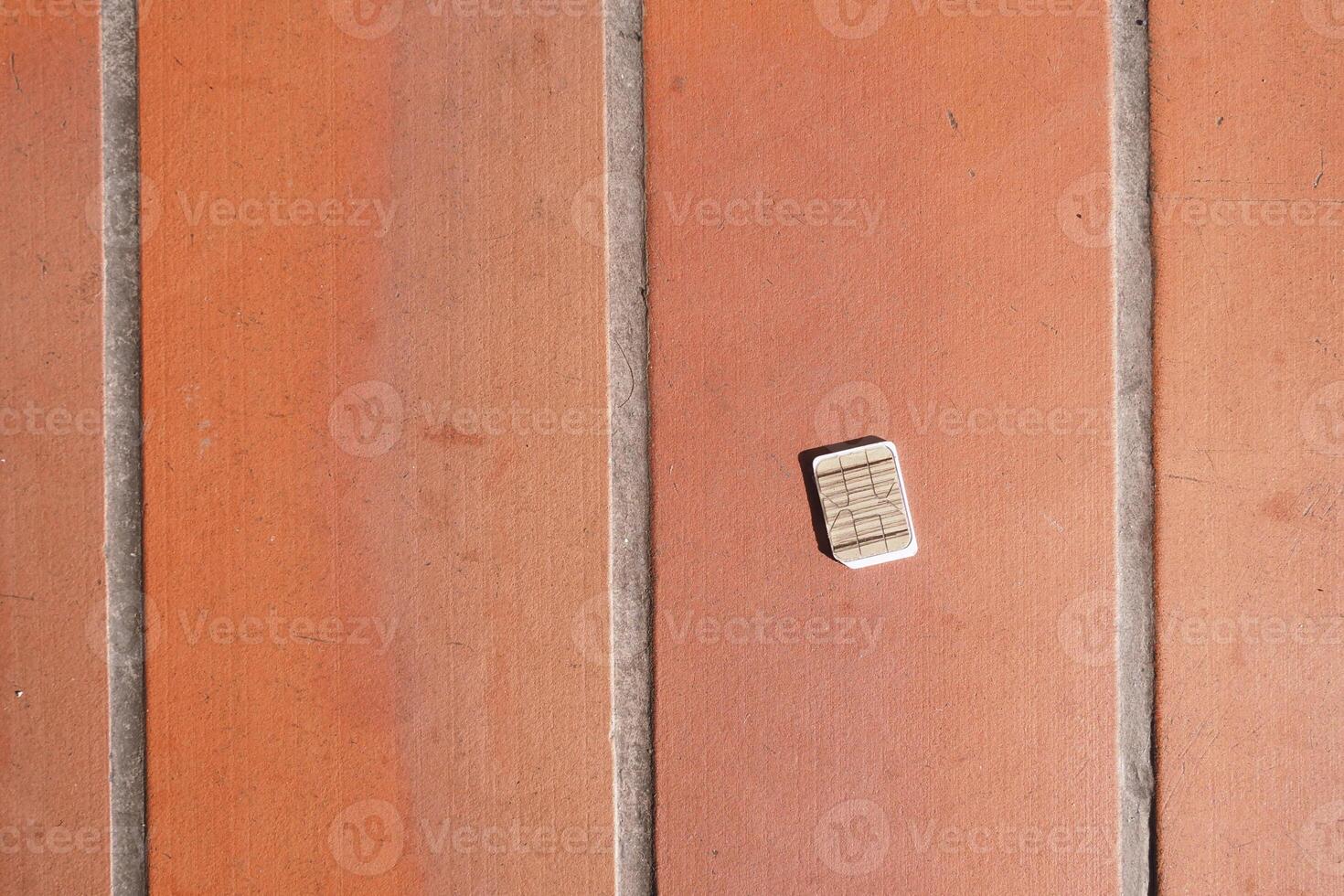 a phone sim card dropped on a tiles floor. lost sim card concept photo