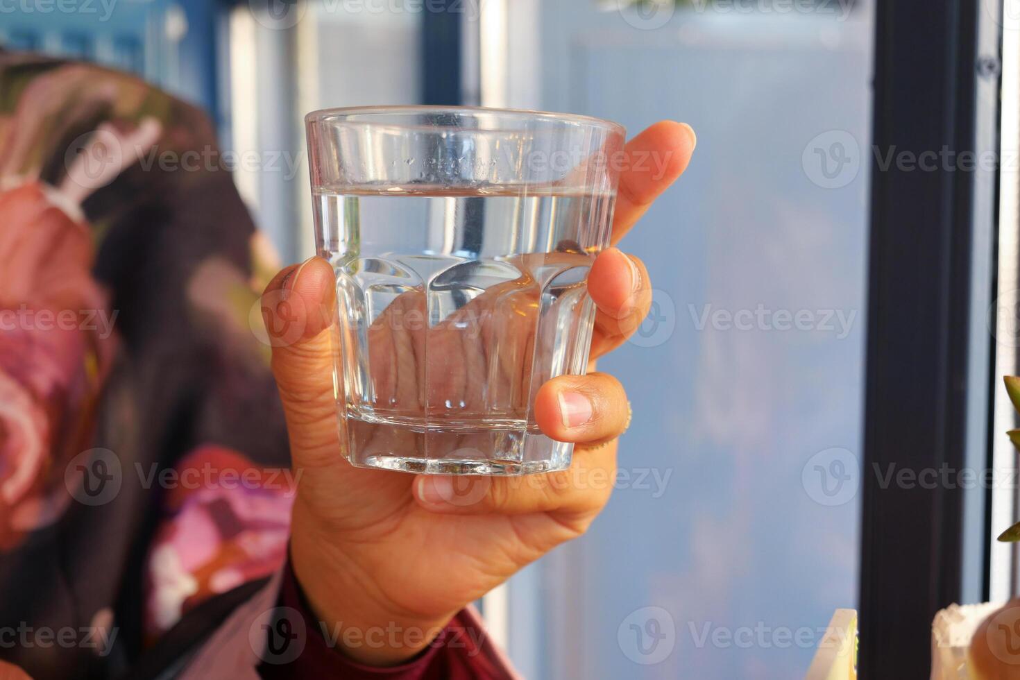 A hand gently holding a glass filled with clear and refreshing water photo