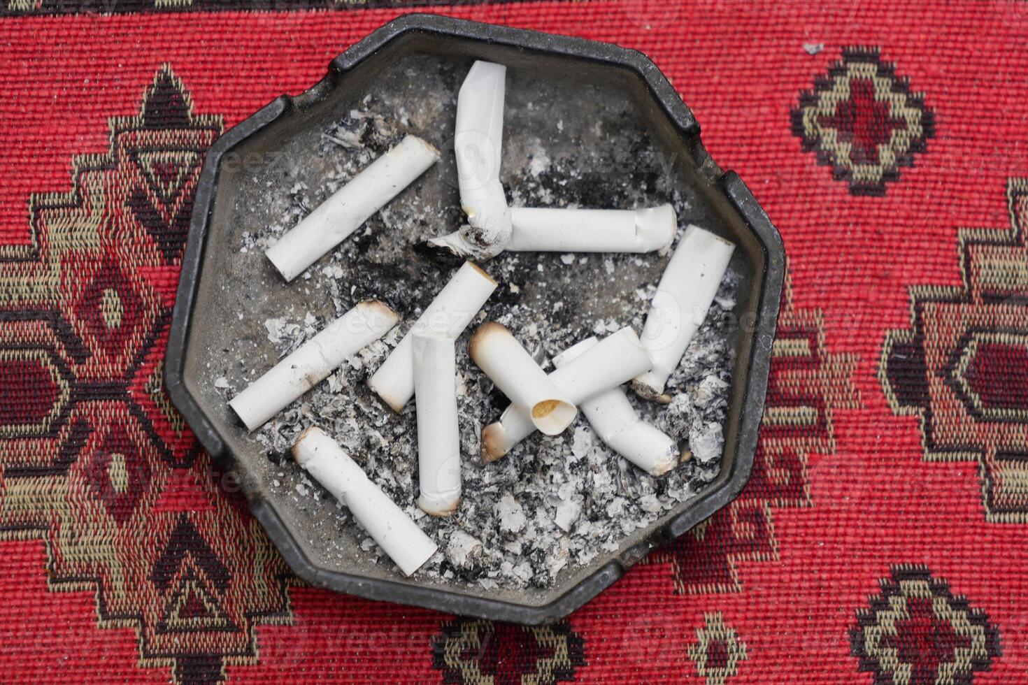 Close up burning cigarette in ashtray on table photo