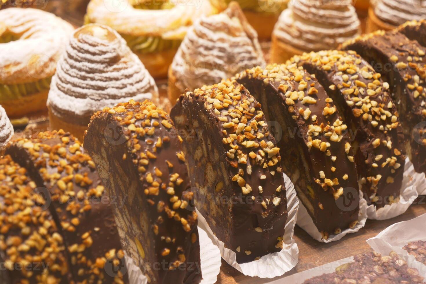 An array of pastries and eclairs are presented in the bakery display case with allure photo