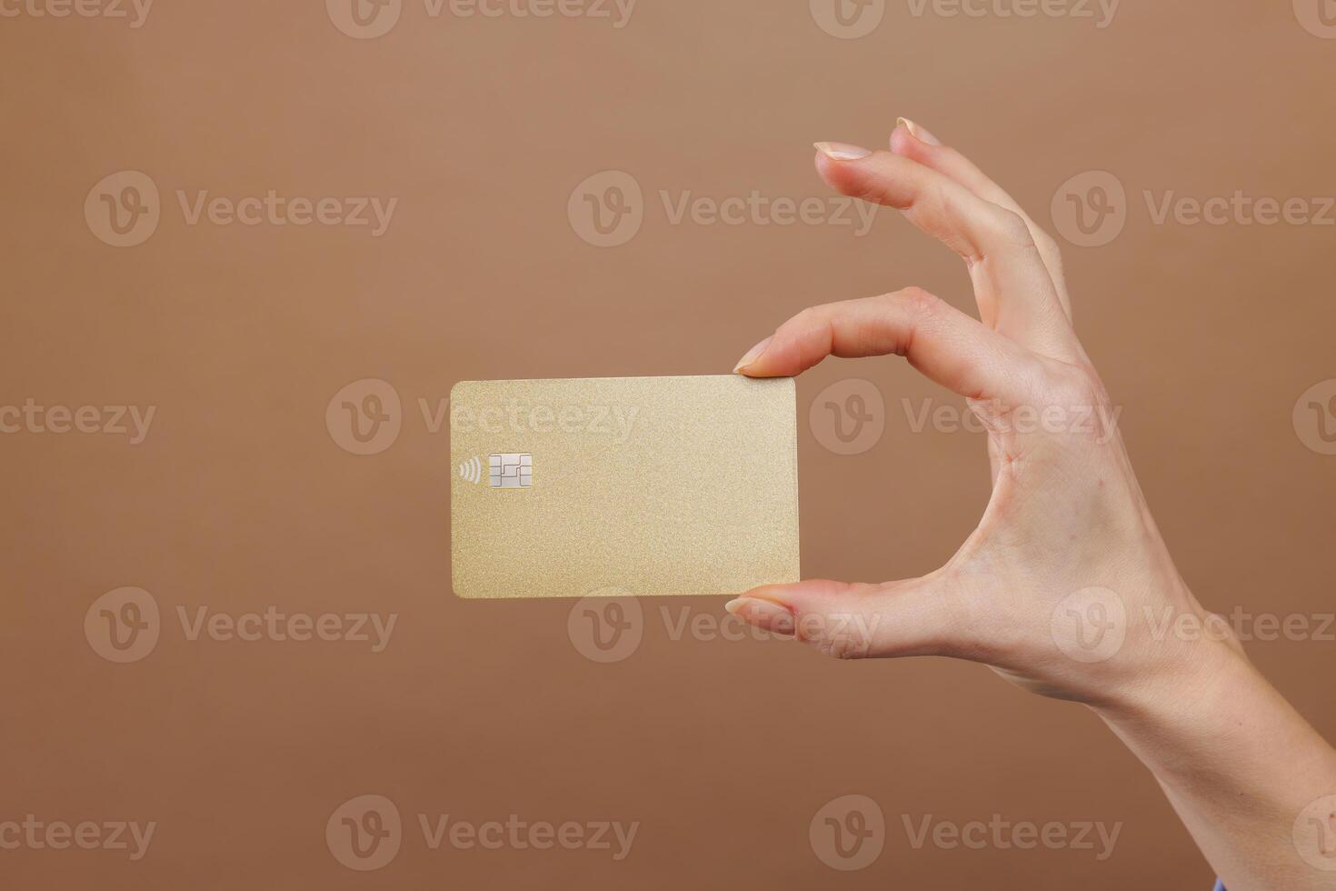 Hand holding credit gold card on beige gold background. photo