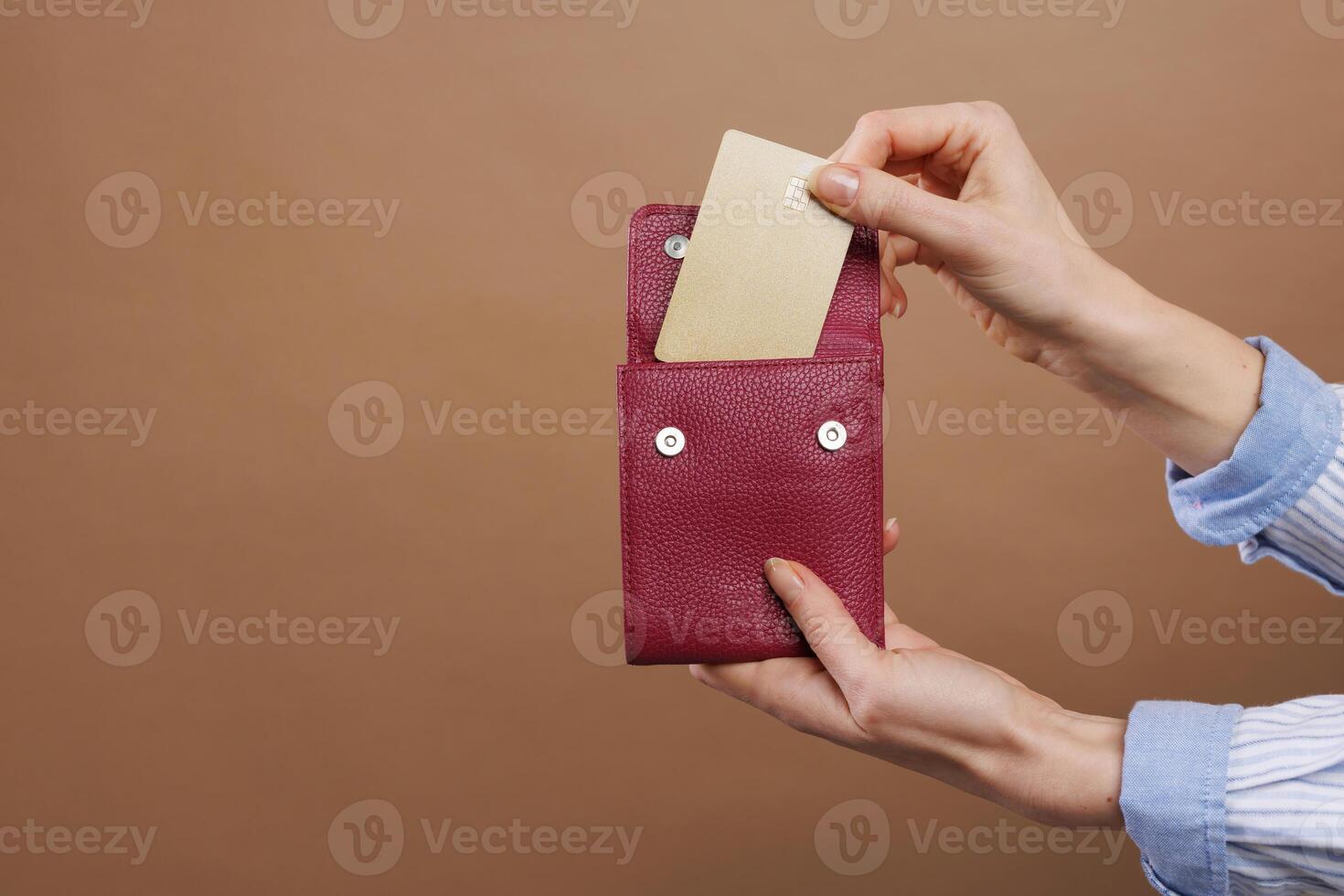 Woman's hand takes out a gold credit card from her wallet on a beige gold background. photo