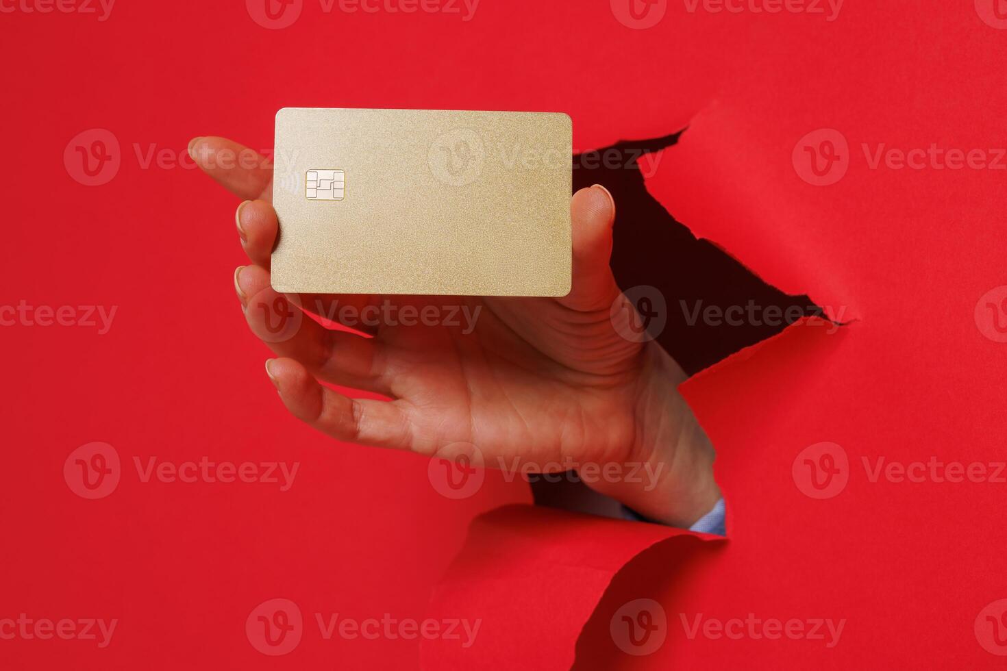 Cropped view of woman hand tearing through paper and holding credit card getting bank loan for purchase isolated on red background. photo