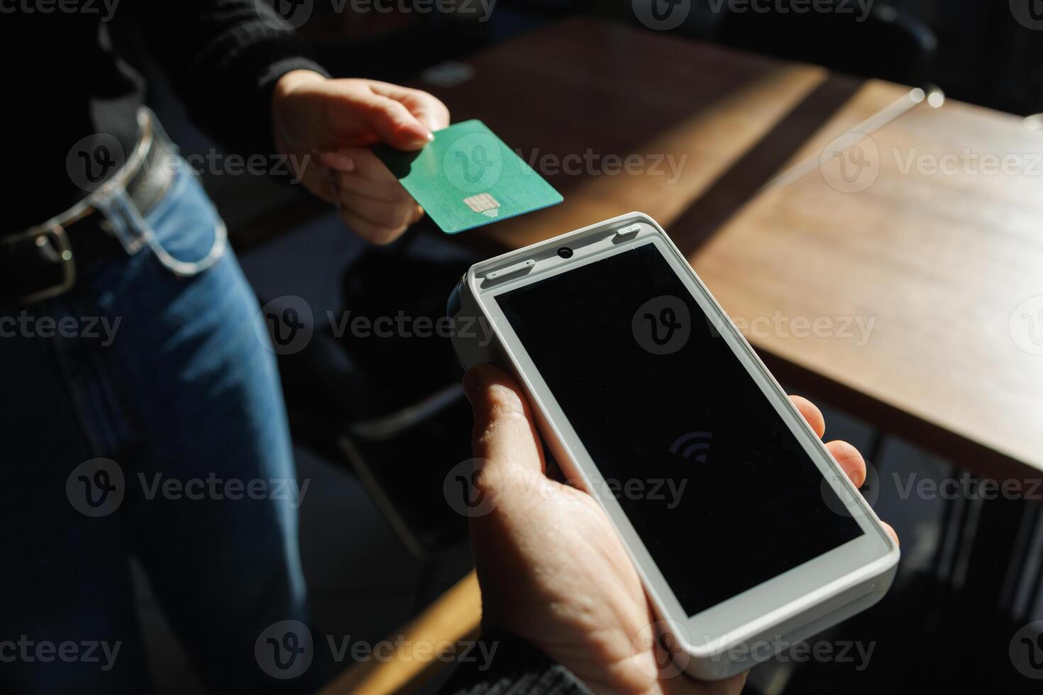A man accepts payment from a customer through a credit card terminal in a store or cafe photo