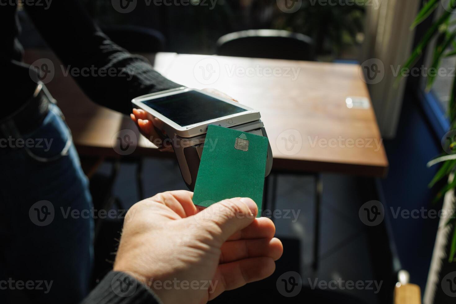 A man accepts payment from a customer through a credit card terminal in a store or cafe photo