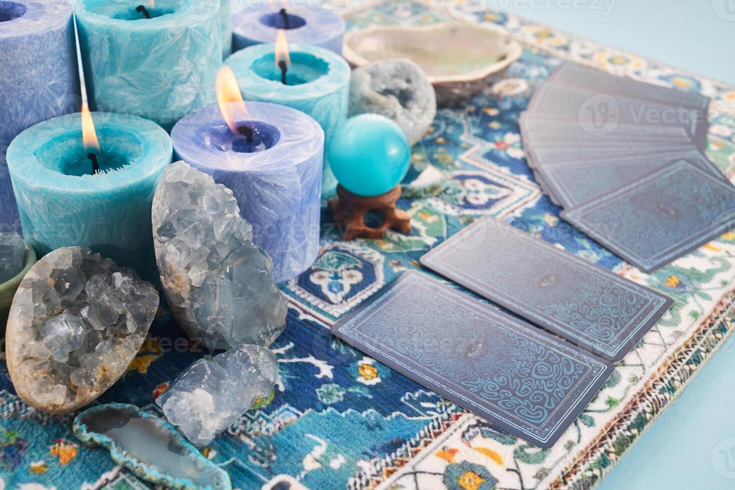 Mystical Card Reading Setup. Blue candles, crystals, and tarot cards on a patterned cloth. photo