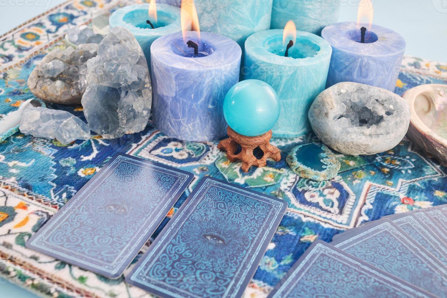 Mystical Card Reading Setup. Blue candles, crystals, and tarot cards on a patterned cloth. photo