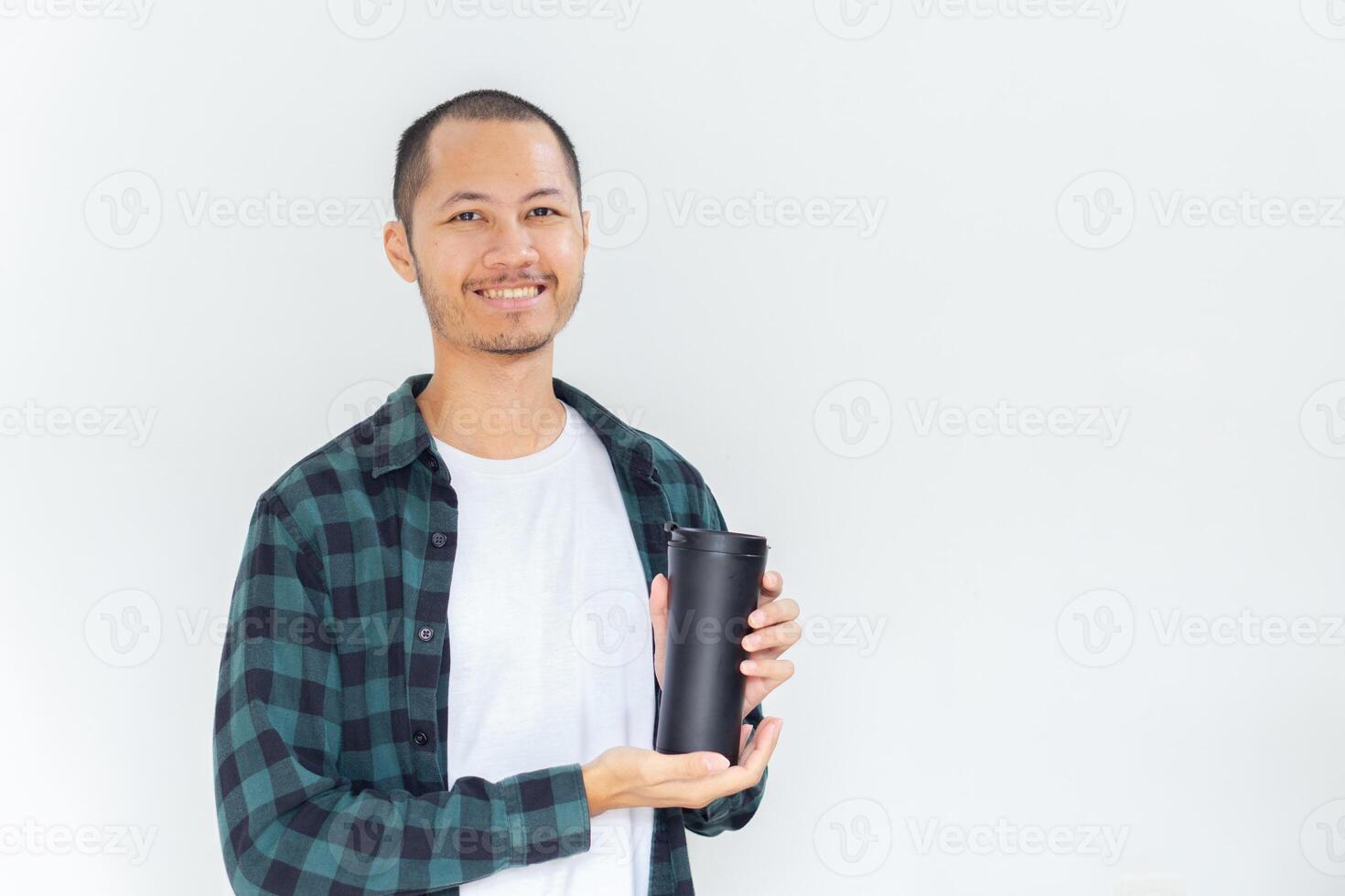 Young asian men wearing flannel and shirt is holding black tumbler with smile in isolated white background photo