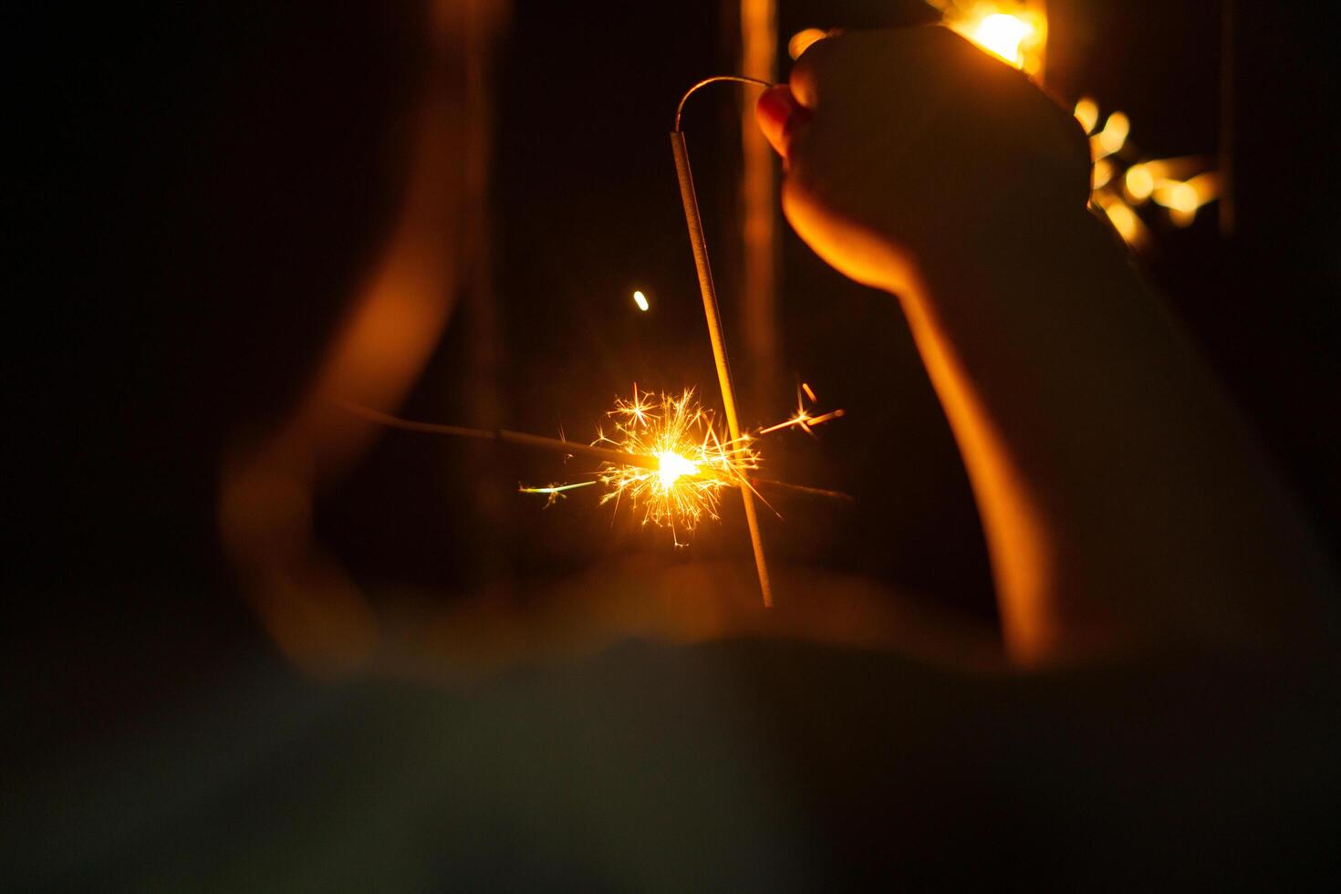 Playing firework sparkles in night with silhouette of hand of kids for new year event photo