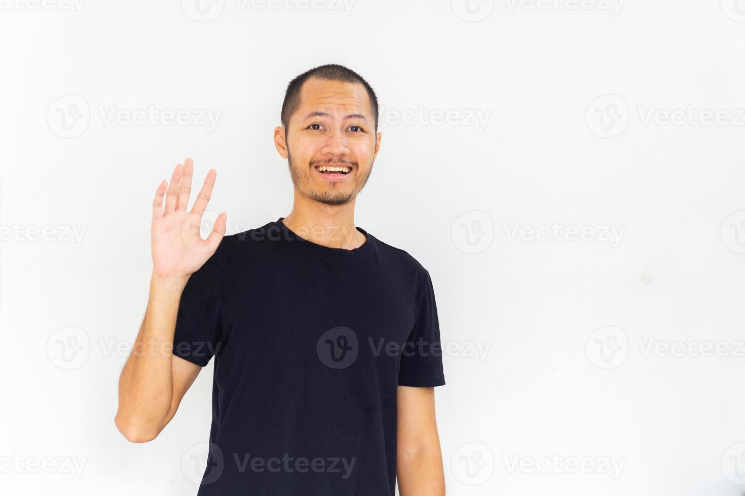 Young man wearing empty black shirt is giving hi sign with hand with isolated white background photo