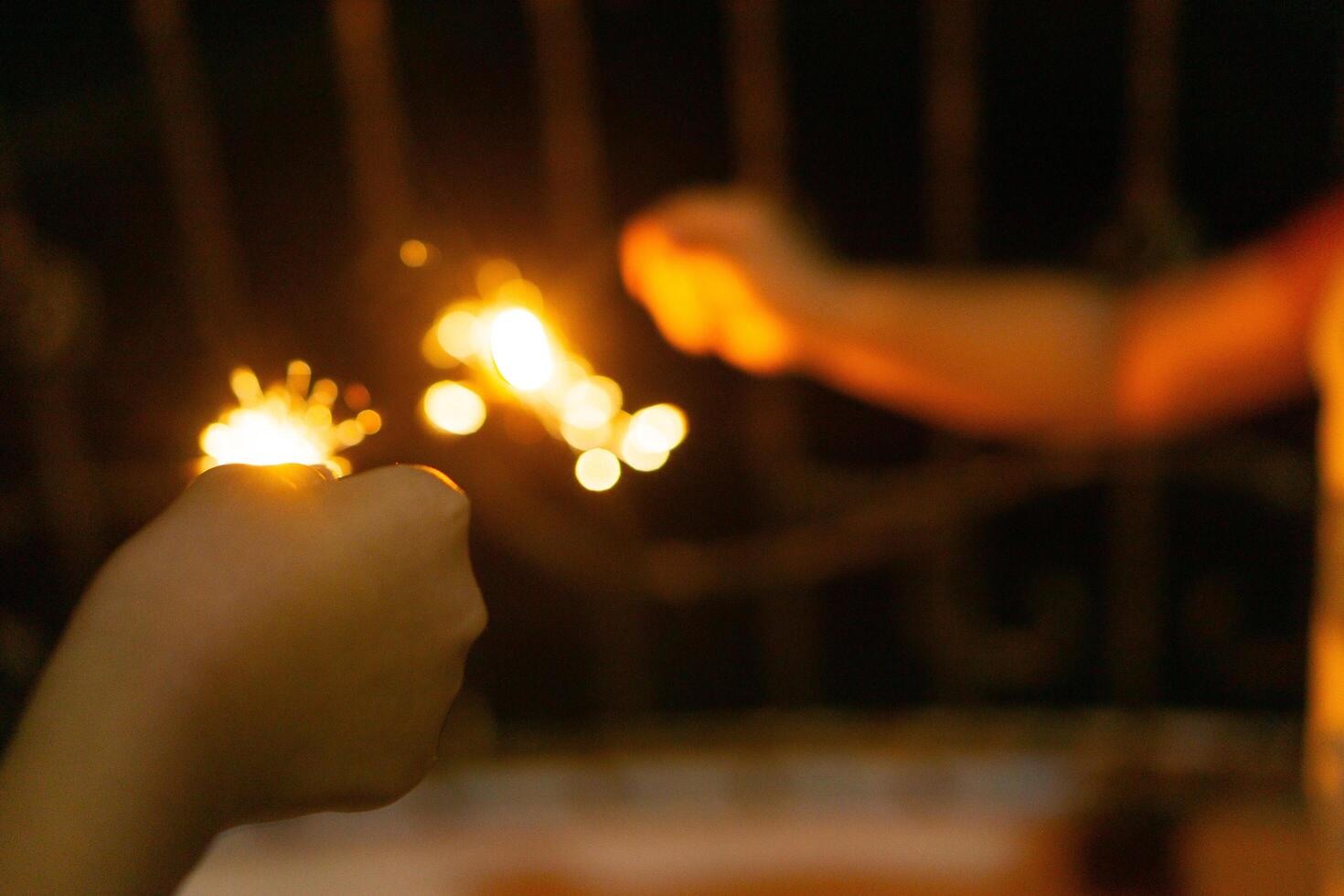 Playing firework sparkles in night with silhouette of hand of kids for new year event photo