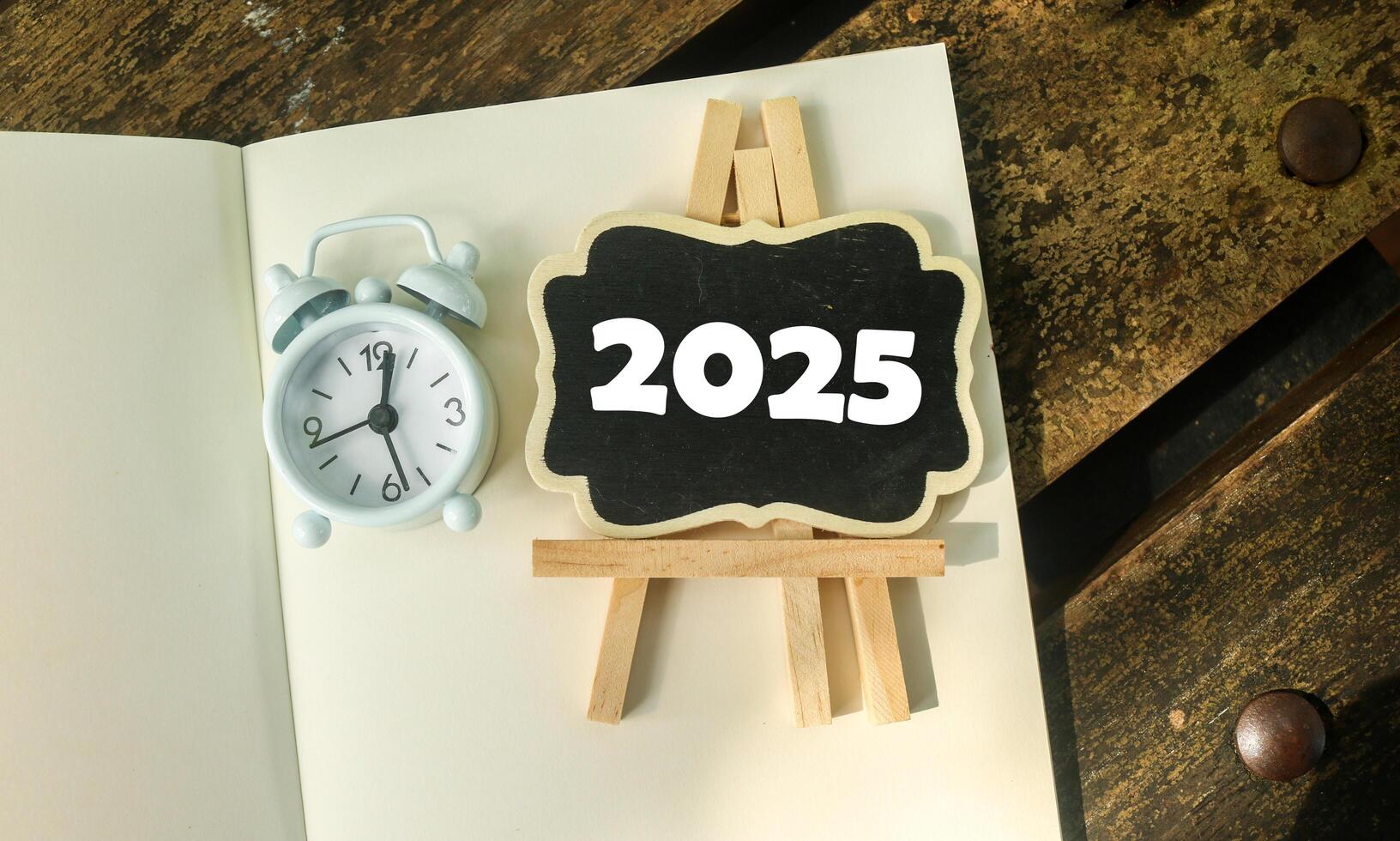 A small wooden-framed blackboard with 2025 on the notebook. Hello new year 2025 photo
