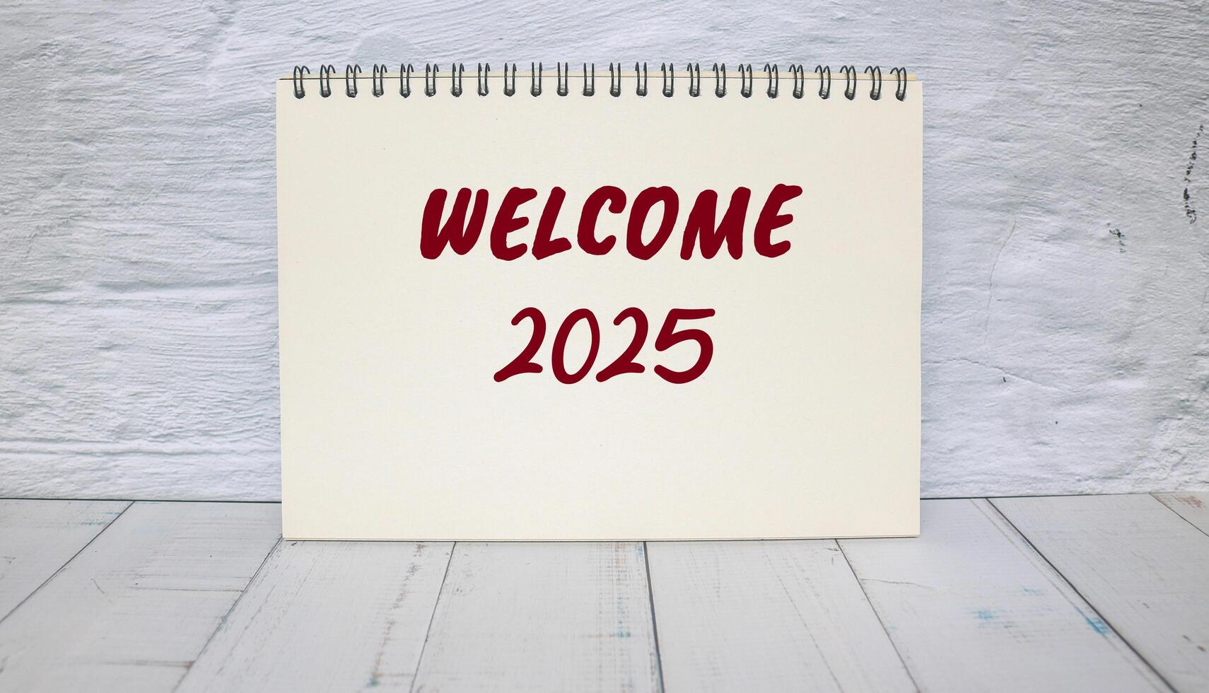 Welcome to 2025 message written on notebook with wall background. Conceptual welcome to 2025 symbol. Copy space. photo