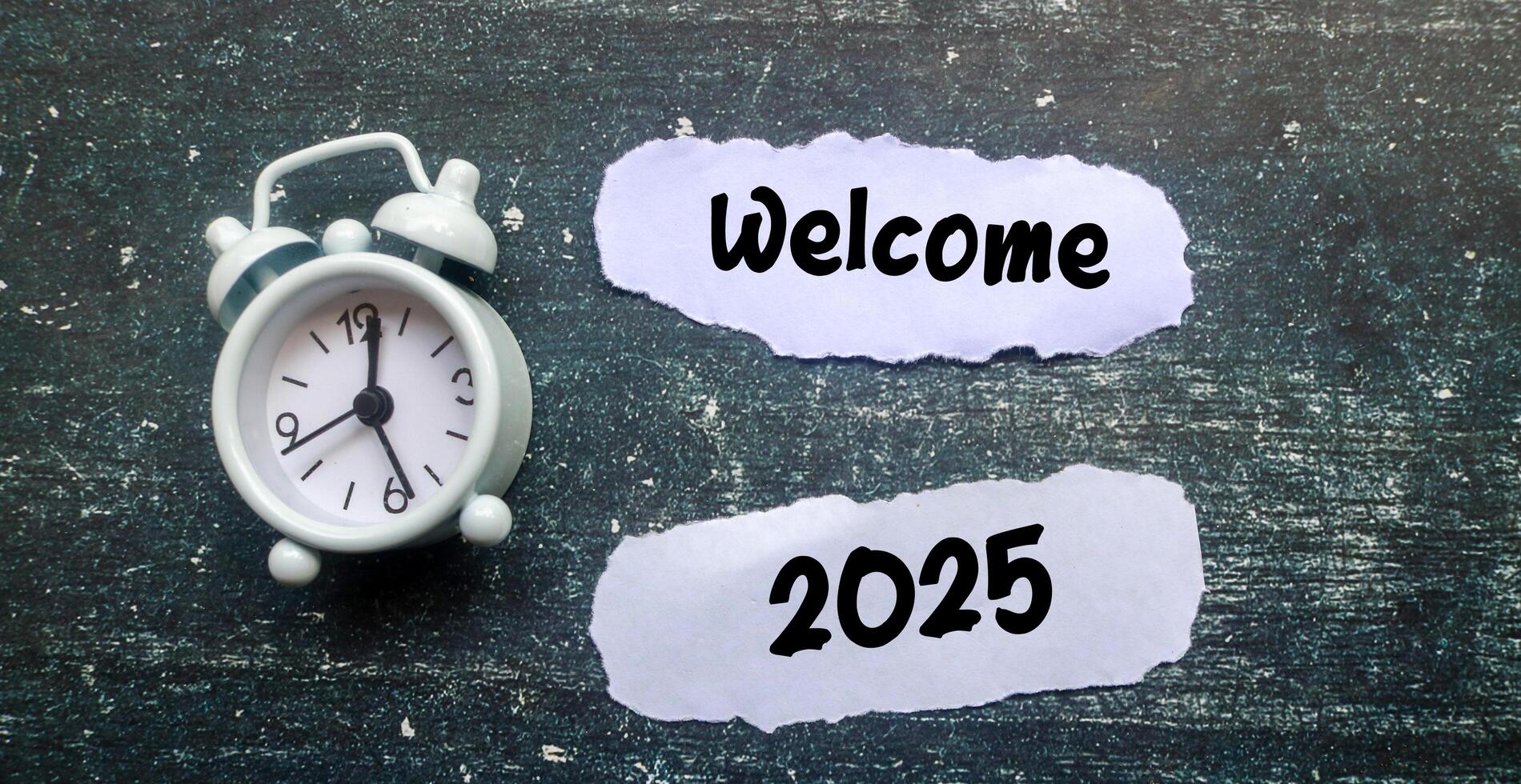 A scrap of paper with the words welcome 2025 surrounded by a clock on the table. New Year 2025 concept, welcoming the new year 2025 photo