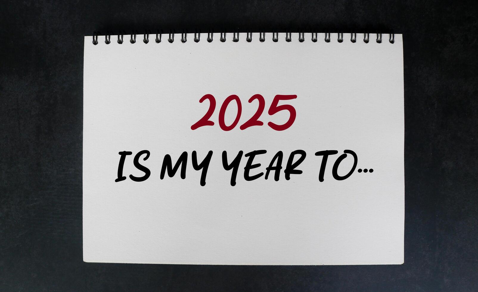 2025 is my year to be on notebook with white desk background. New year concept with typographic 2025 on notebook. Motivational words for the new year 2025 photo