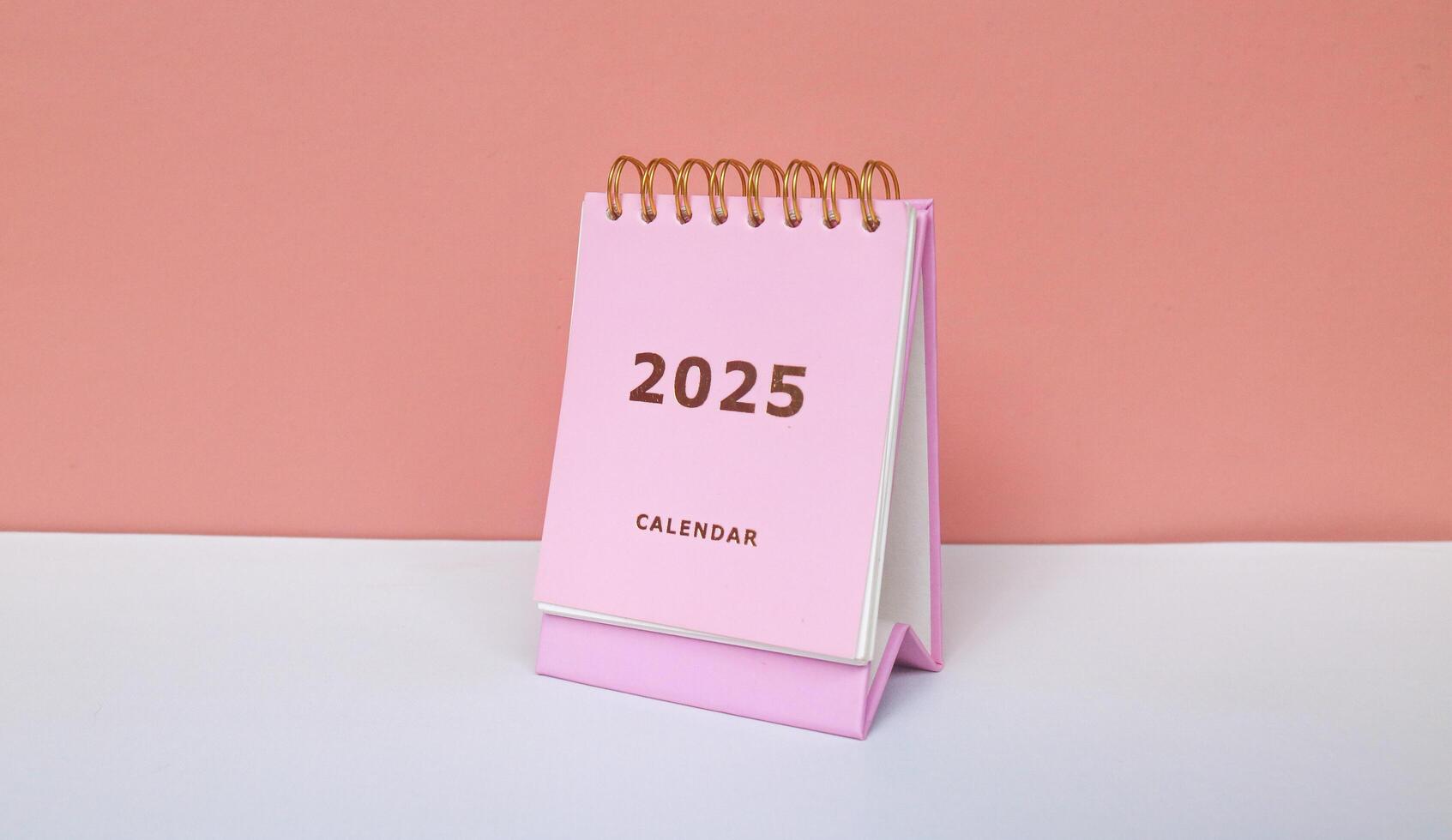 2025 calendar in pink isolated on pink background. Calendar and Note Pad Happy New year 2025. 2025 New Year resolutions goal, plan, and action concept photo