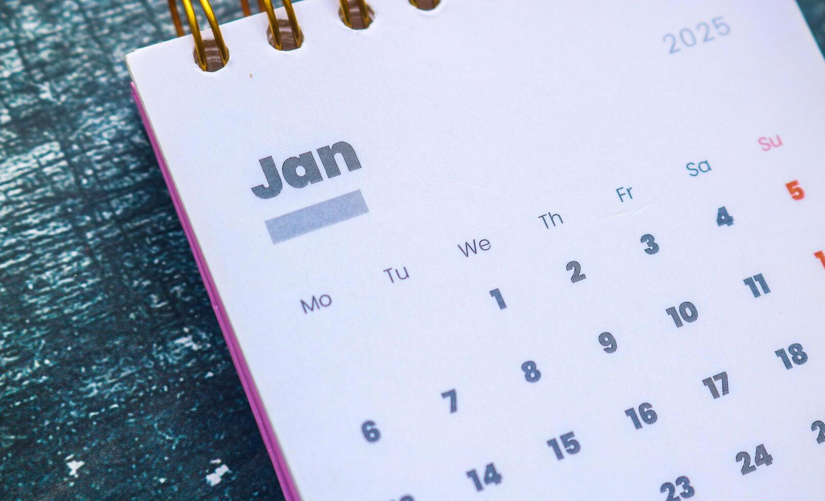 Close up of January 2025 in the pink 2025 calendar on the table. Calendar and Note Pad Happy New Year 2025. Zoomed in first of January 2025 in the calendar photo