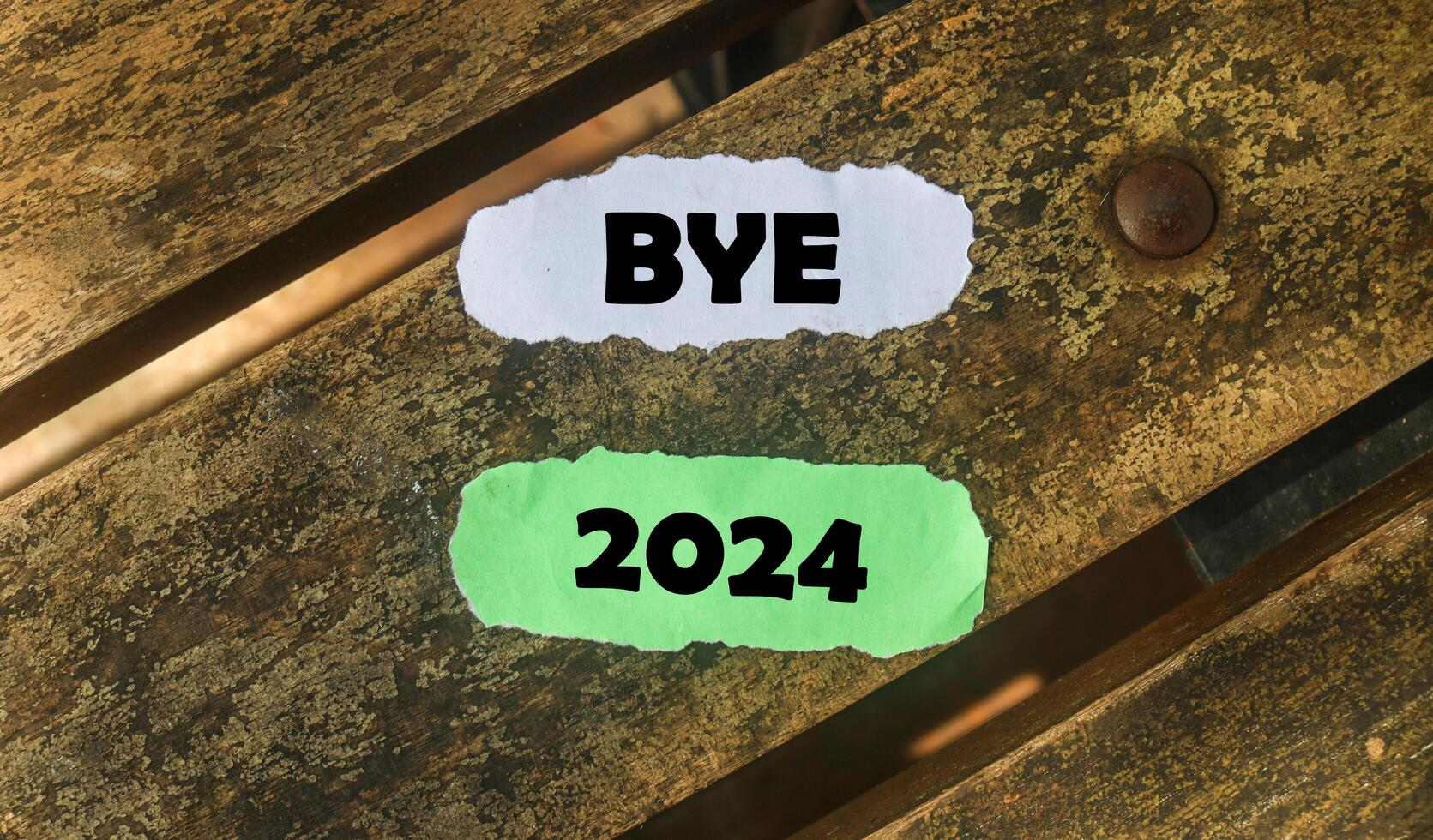 Inscription on the word goodbye 2024 on wooden table background. Bye 2024 on paper, hello 2025 photo
