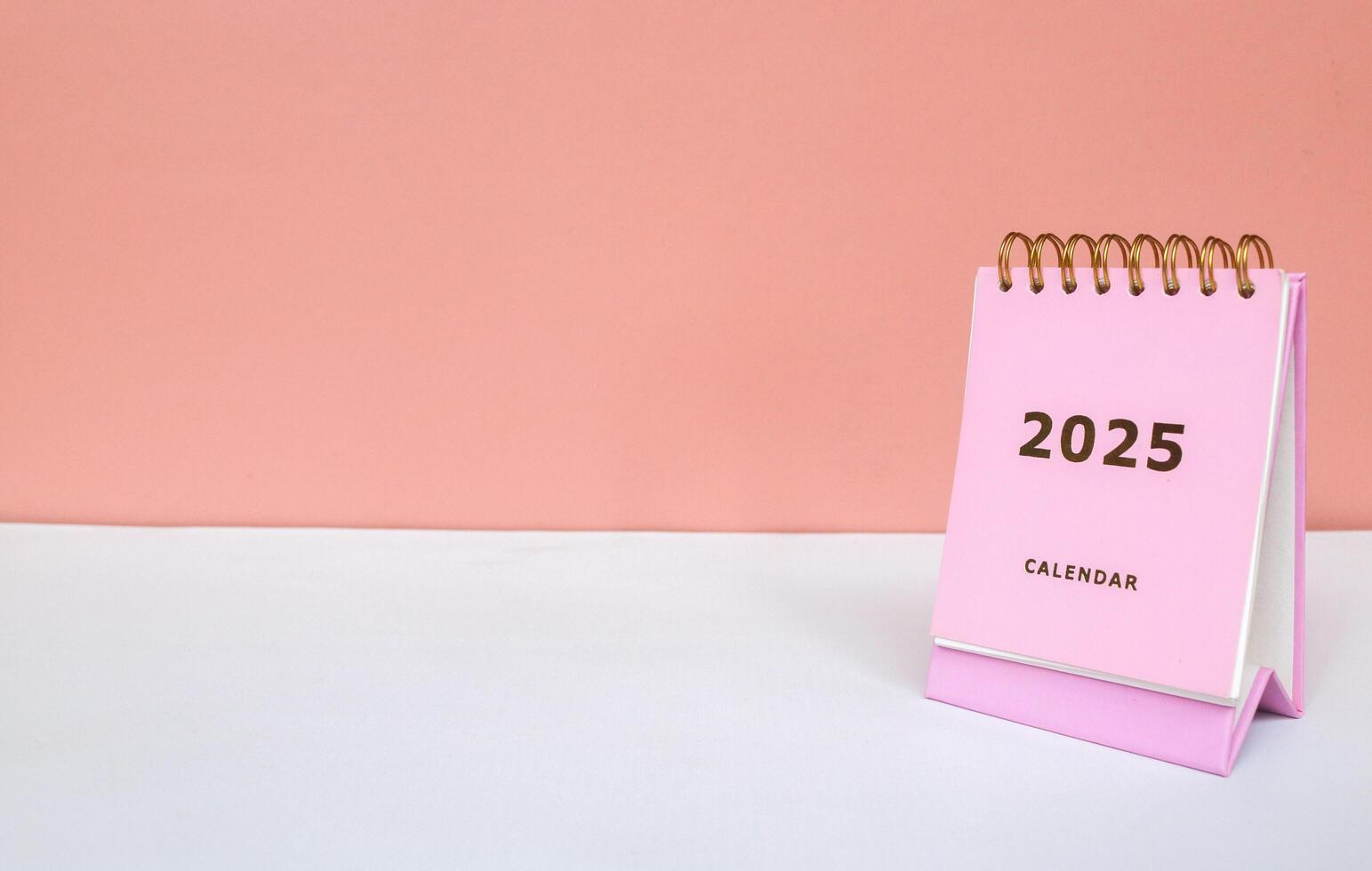 2025 calendar in pink isolated on pink background. Calendar and Note Pad Happy New year 2025. 2025 New Year resolutions goal, plan, and action concept photo