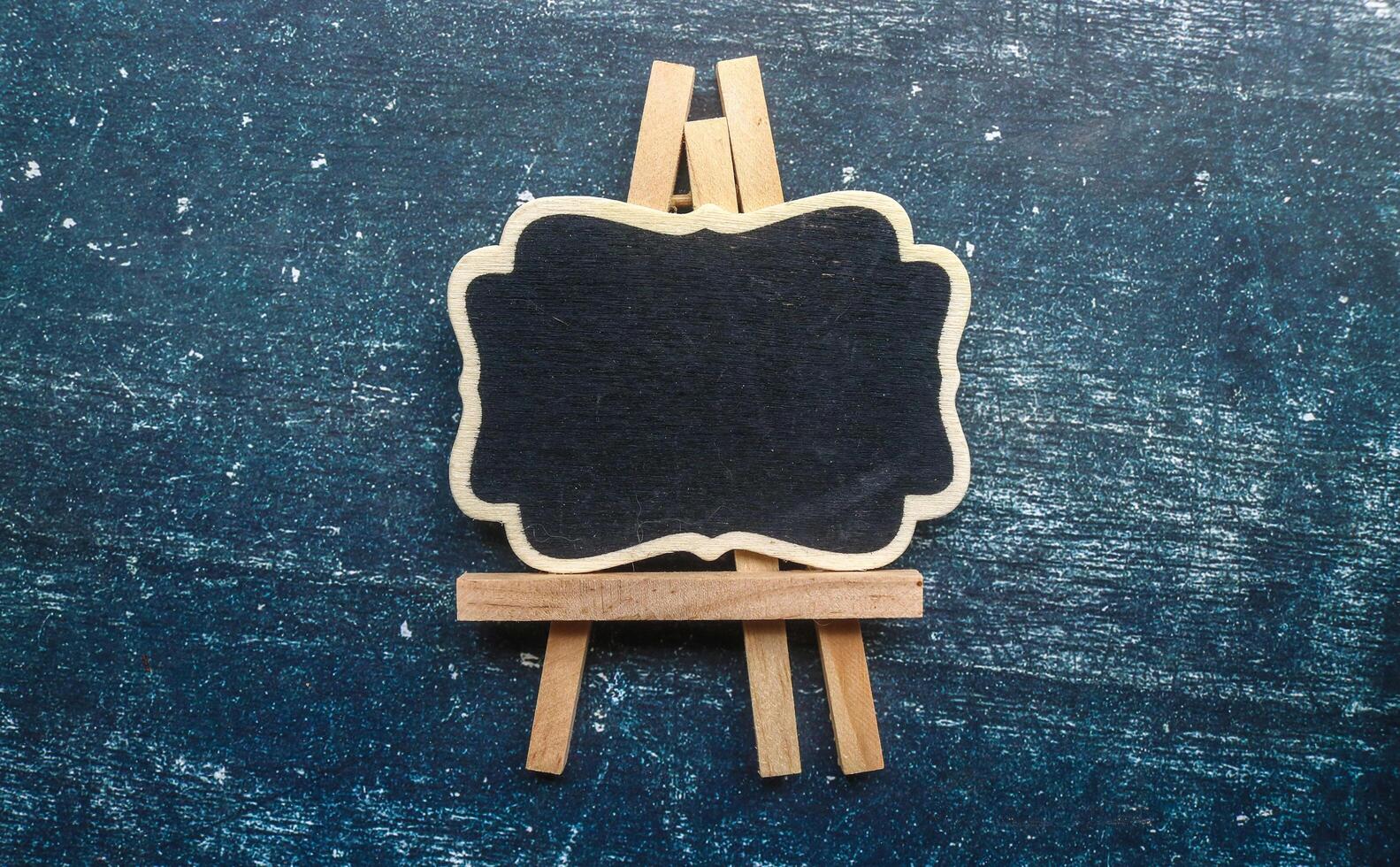 Wooden easel mini blackboard with faded chalk surface, isolated on gray background. Blank space for text photo